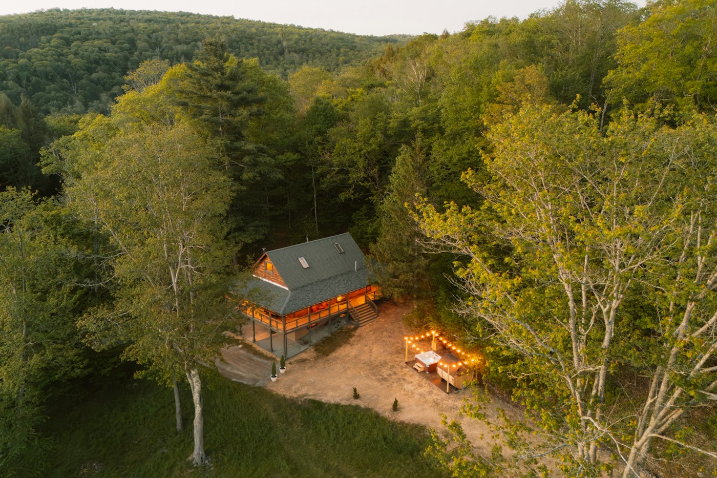 Chalet en forêt avec un spa éclairé au crépuscule
