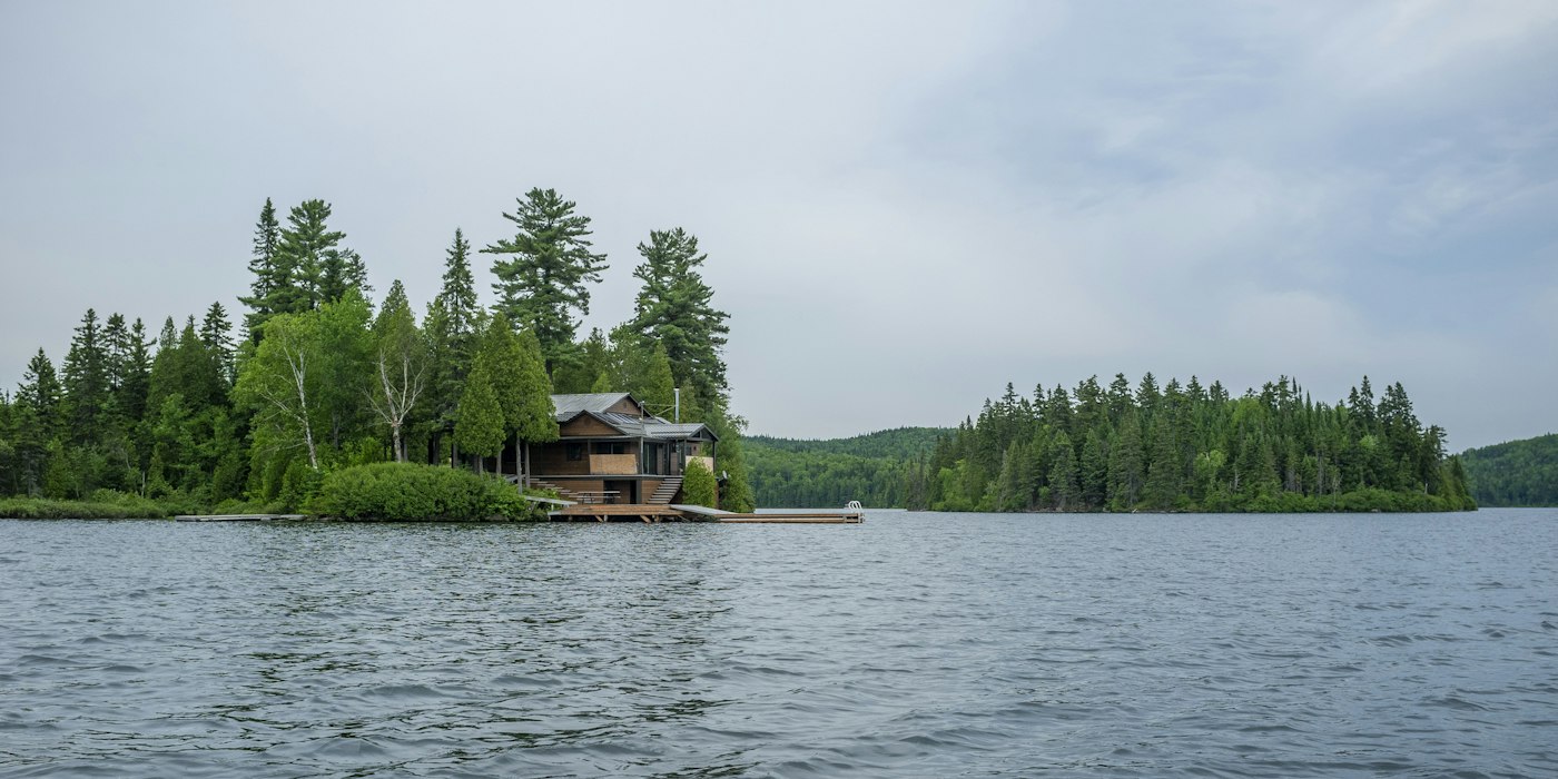 Chalet au bord d’un lac avec un quai parmi les pins